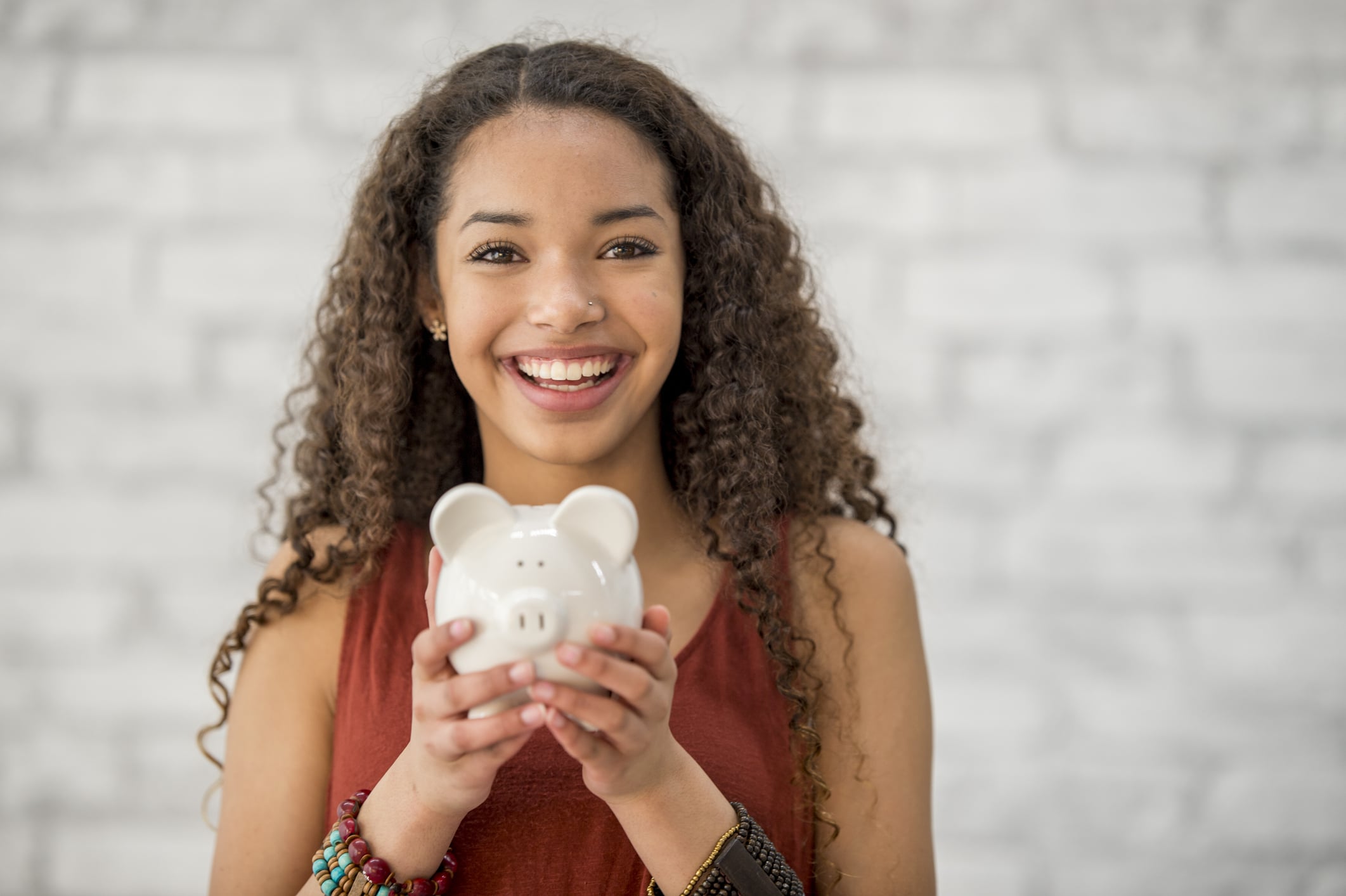 Smiling person holding a piggy bank, symbolizing How Much Money Can You Earn as an Egg Donor with RMA of Michigan